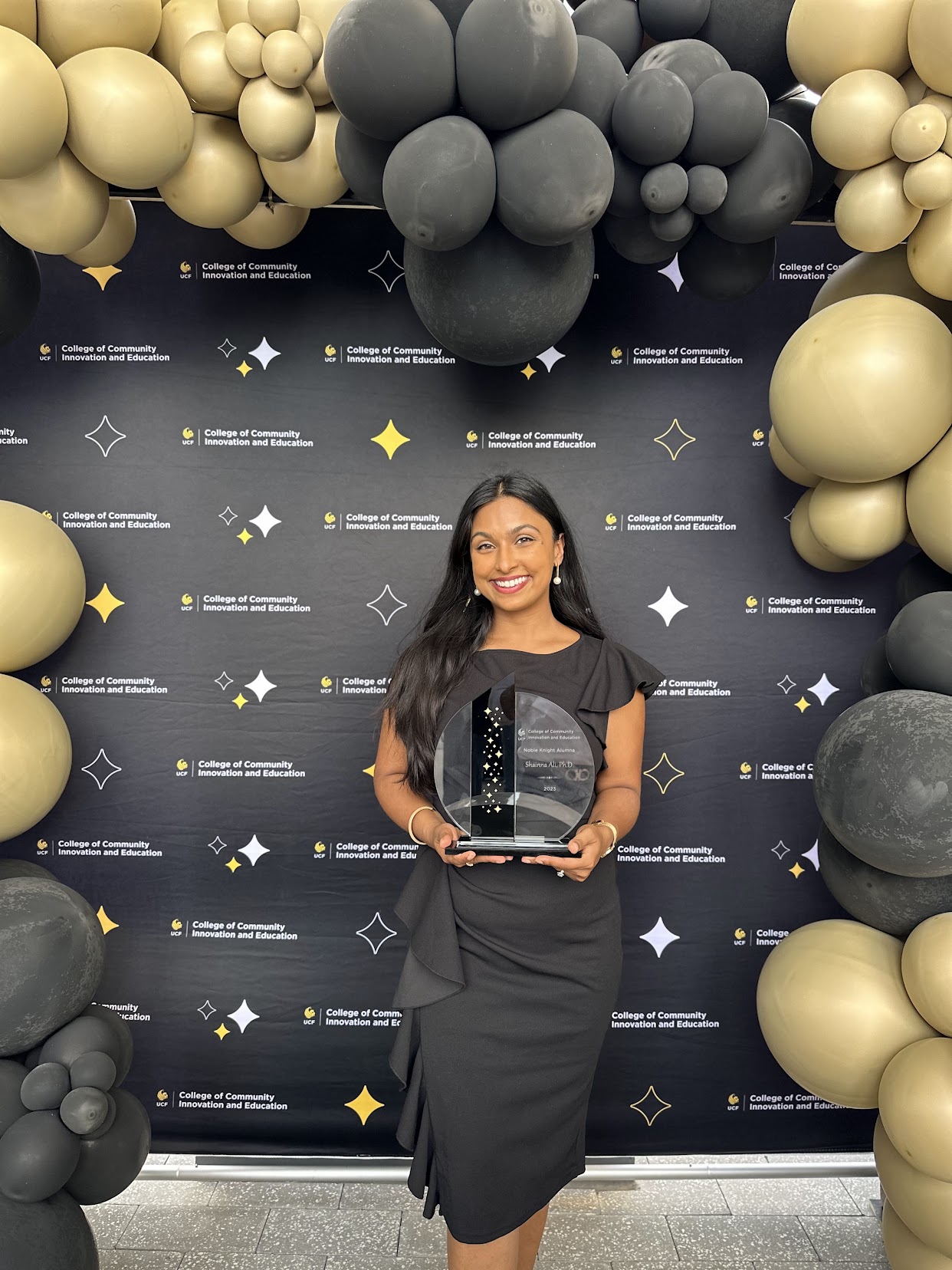 Dr. Shainna holding the UCF Noble Knight Alumni Award